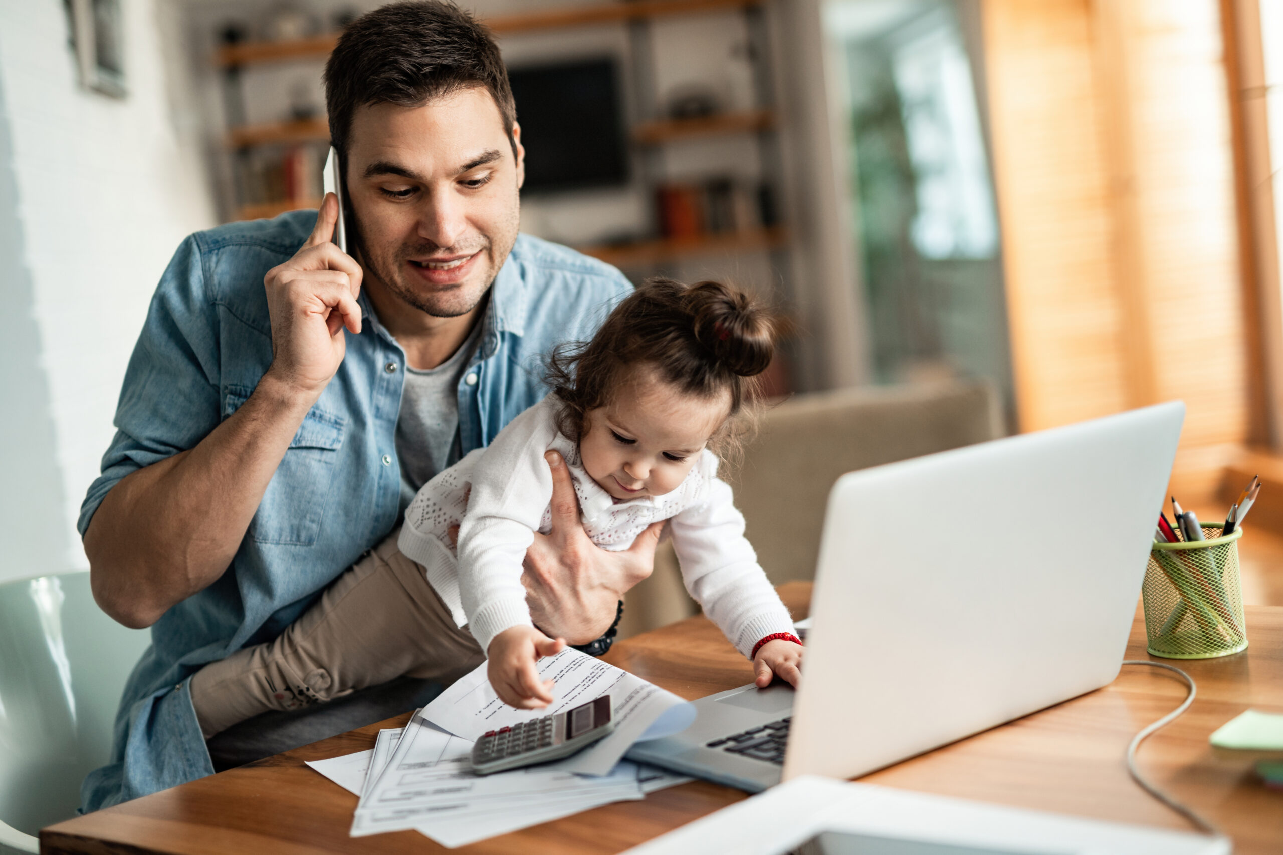 Young,Working,Father,Talking,On,The,Phone,While,Babysitting,His